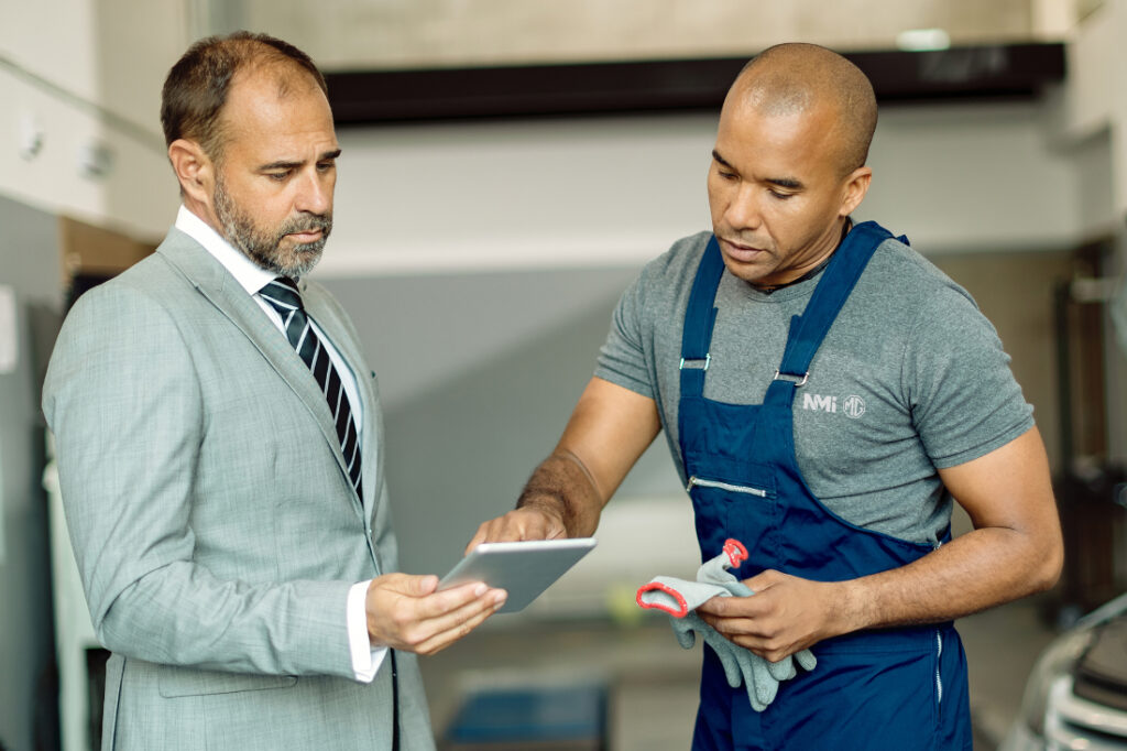 black mechanic and his manager working on touchpad in auto repai